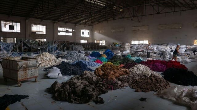 Des amoncellements de tissus de l’industrie textile sont abandonnés au sol dans une vieille usine textile.